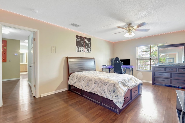 bedroom featuring baseboards, a textured ceiling, visible vents, and dark wood-type flooring