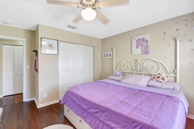 bedroom featuring dark wood-style floors, a closet, visible vents, a ceiling fan, and baseboards