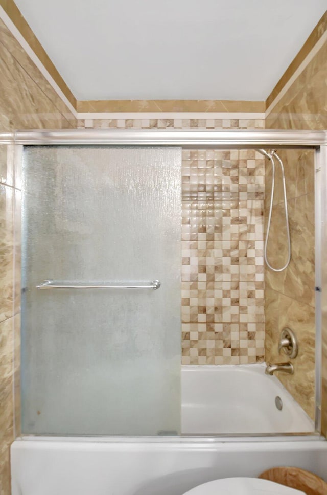 bathroom featuring enclosed tub / shower combo and toilet