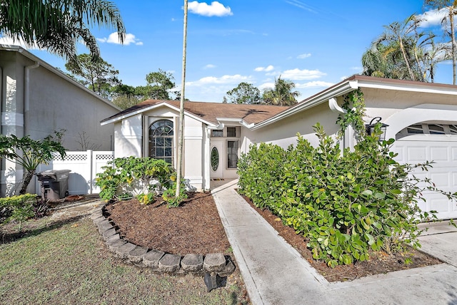 view of front of home with a garage, fence, and stucco siding