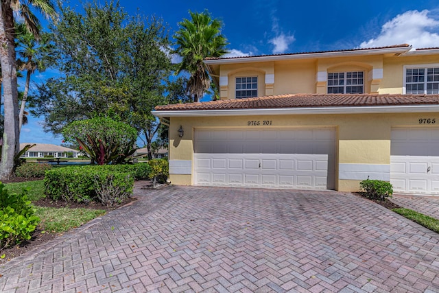 view of front facade with decorative driveway, a tile roof, and stucco siding