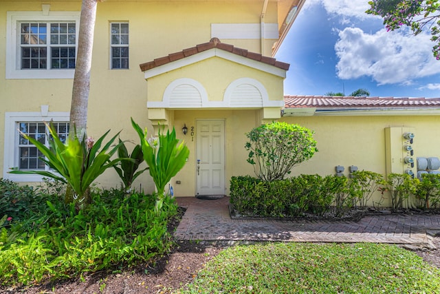 property entrance with a tile roof and stucco siding