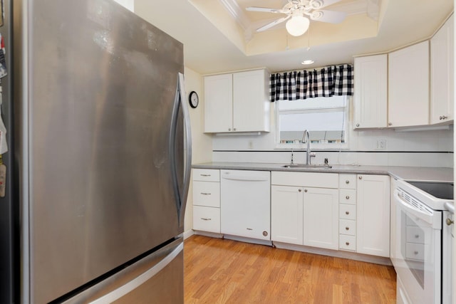 kitchen with white appliances, white cabinetry, a raised ceiling, and a sink