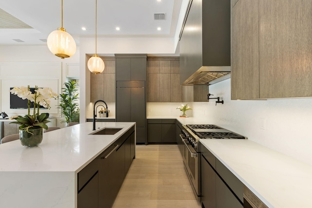 kitchen featuring a large island, extractor fan, decorative light fixtures, high end stainless steel range, and sink