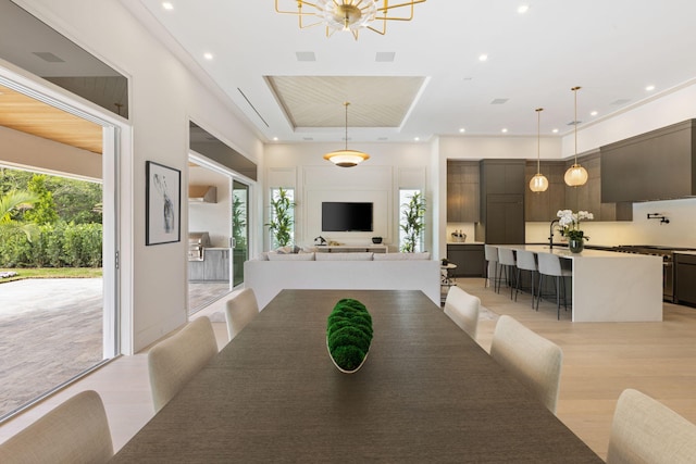 dining space with a healthy amount of sunlight, a tray ceiling, and light wood-type flooring