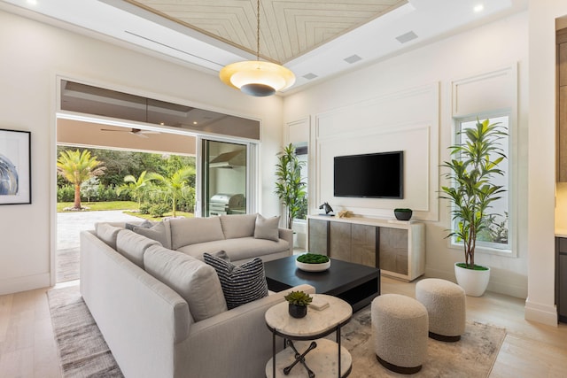 living room with light hardwood / wood-style floors and a raised ceiling