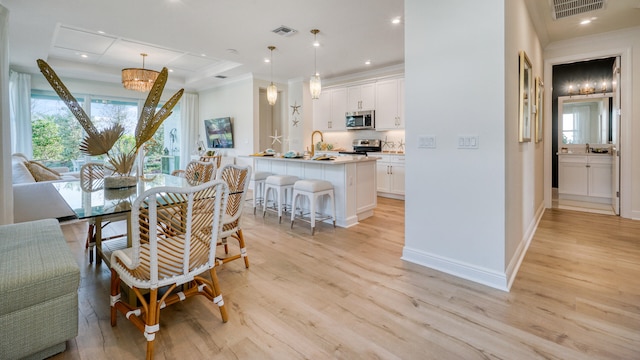 dining area with ornamental molding and light hardwood / wood-style flooring