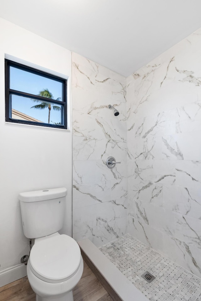 bathroom with tiled shower, wood-type flooring, and toilet