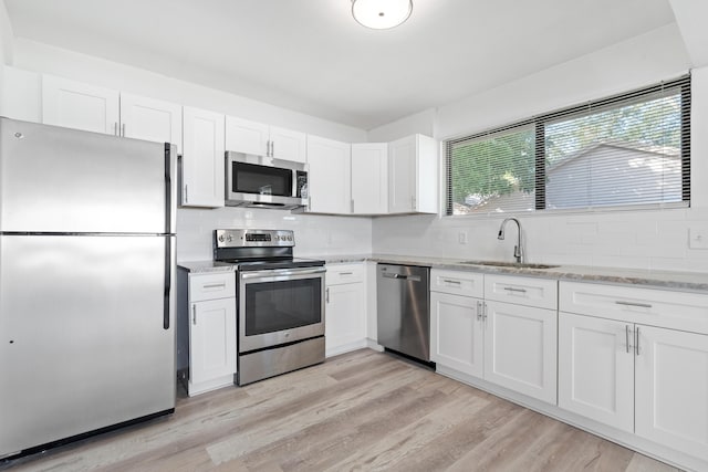 kitchen with appliances with stainless steel finishes, decorative backsplash, light hardwood / wood-style floors, sink, and white cabinetry