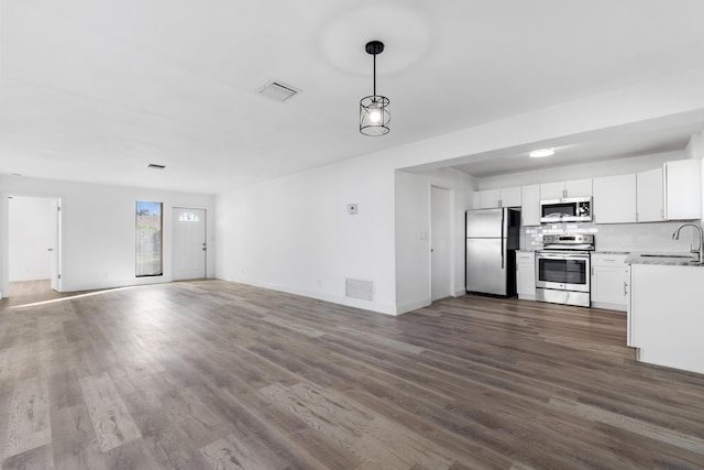 kitchen with sink, white cabinetry, pendant lighting, stainless steel appliances, and dark wood-type flooring