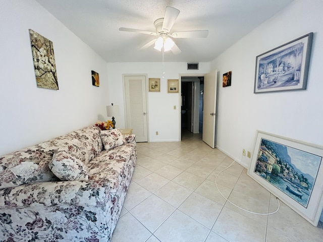 living area featuring visible vents, baseboards, ceiling fan, a textured ceiling, and light tile patterned flooring