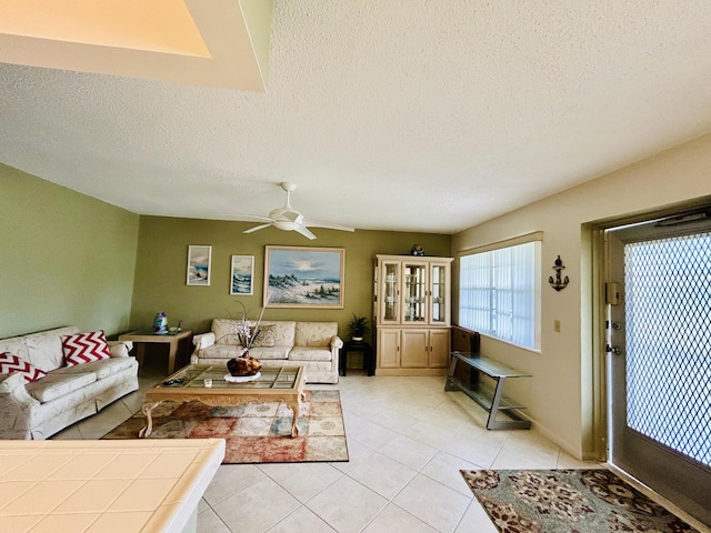 living room featuring light tile patterned floors, ceiling fan, and a textured ceiling