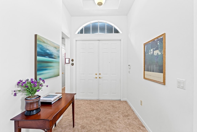 entrance foyer with a tray ceiling and baseboards