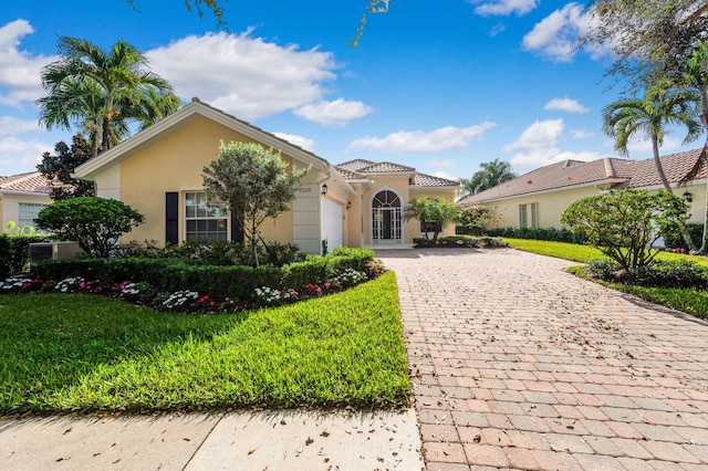 mediterranean / spanish house featuring a front yard and a garage