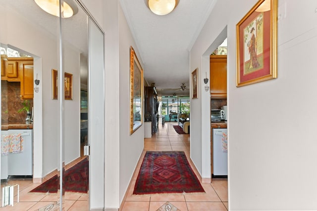 hall featuring a toaster, a textured ceiling, baseboards, and light tile patterned floors