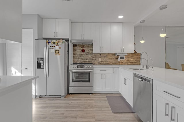 kitchen featuring appliances with stainless steel finishes, white cabinets, a sink, and decorative light fixtures