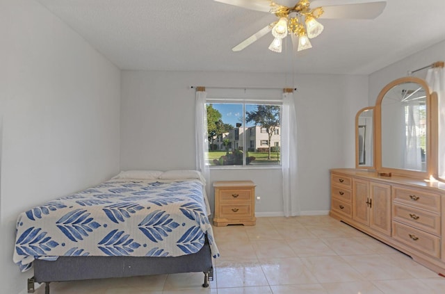 bedroom with a ceiling fan, light tile patterned flooring, a textured ceiling, and baseboards