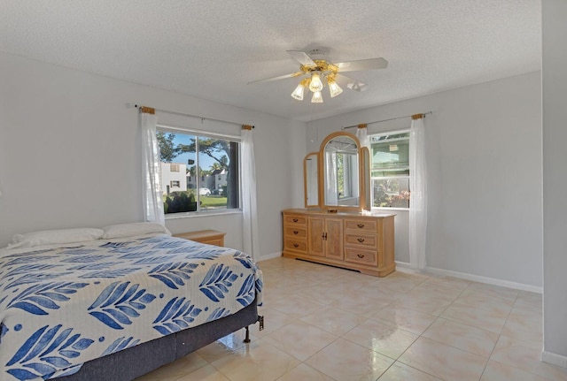 bedroom with a textured ceiling, light tile patterned floors, a ceiling fan, and baseboards