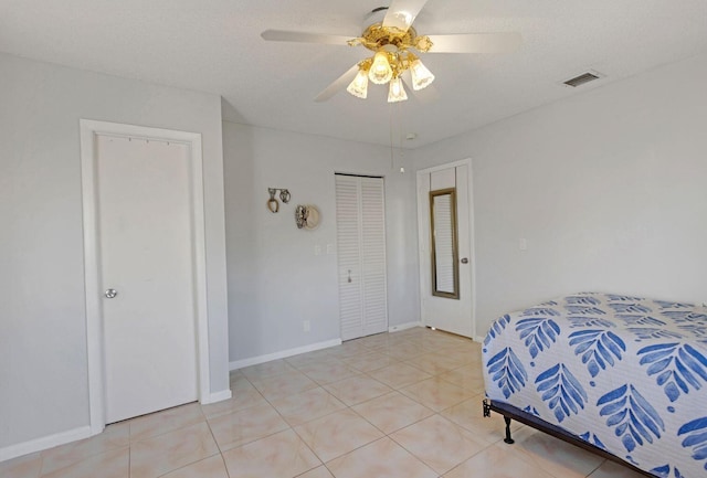 bedroom featuring ceiling fan, light tile patterned floors, a textured ceiling, visible vents, and baseboards