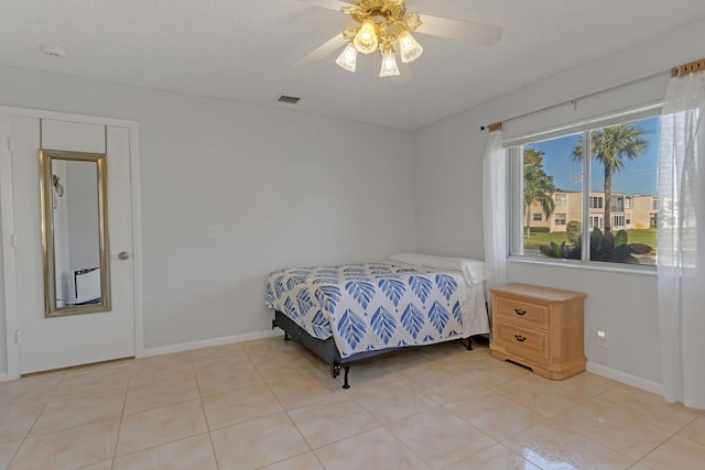 bedroom featuring light tile patterned floors, visible vents, baseboards, ceiling fan, and a textured ceiling