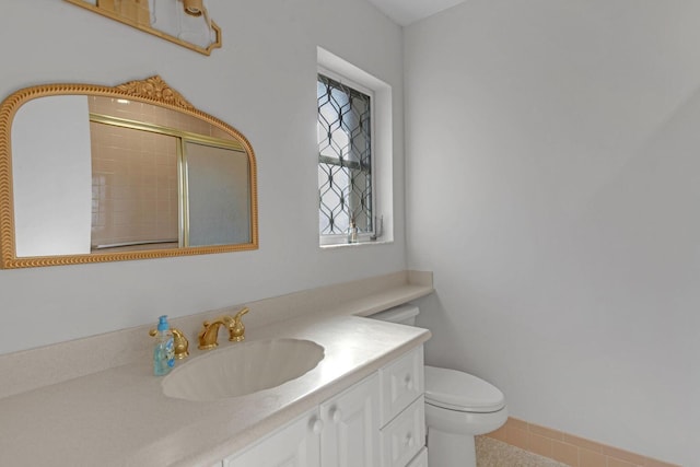 full bathroom featuring toilet, tiled shower, and vanity