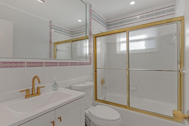 bathroom with tasteful backsplash, toilet, enclosed tub / shower combo, vanity, and tile walls