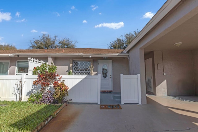 view of exterior entry featuring fence and stucco siding