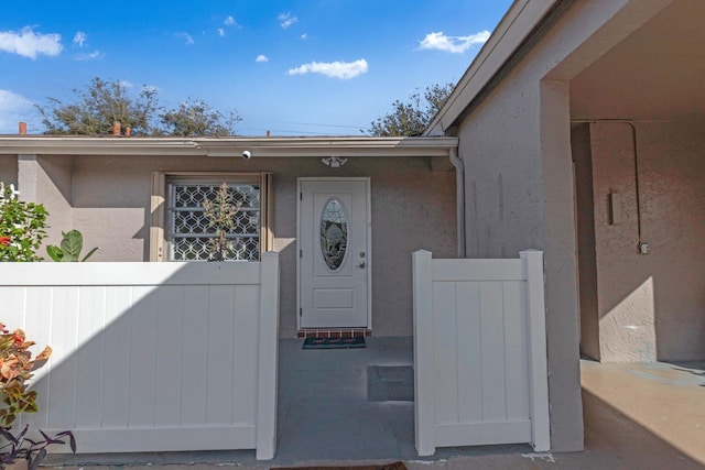 property entrance with fence and stucco siding