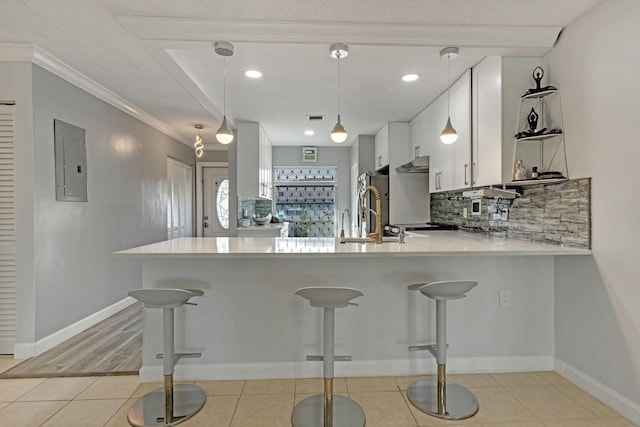 kitchen with electric panel, white cabinets, decorative light fixtures, a peninsula, and light countertops