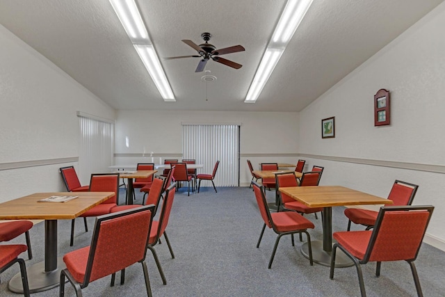 dining space featuring a textured ceiling, ceiling fan, vaulted ceiling, and carpet flooring