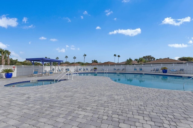 community pool with a patio area and fence