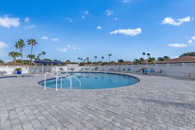 community pool with a patio area and fence