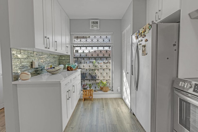 kitchen featuring stainless steel appliances, white cabinets, light countertops, and light wood-style floors