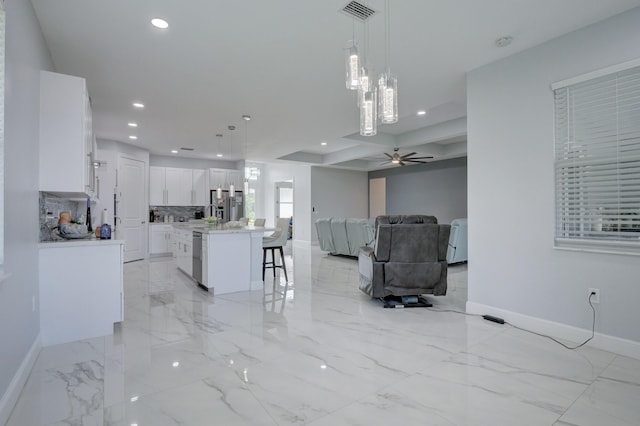 kitchen featuring open floor plan, a kitchen island, decorative light fixtures, and white cabinetry