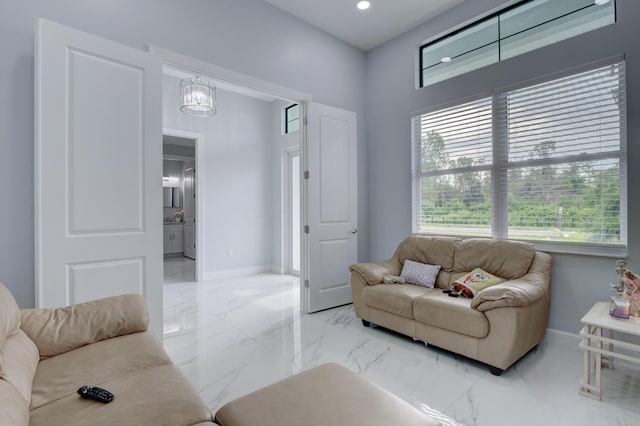 living room featuring marble finish floor, baseboards, and a chandelier