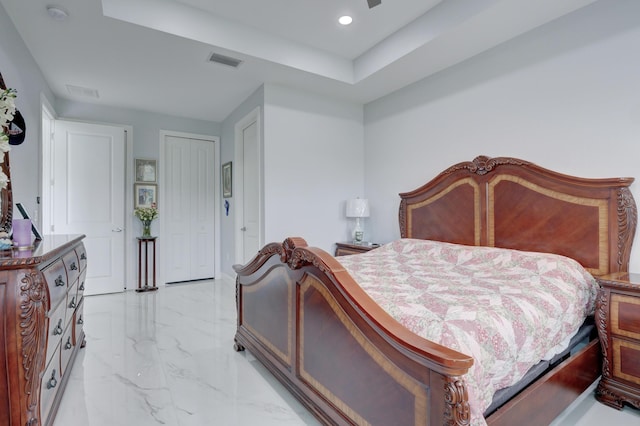 bedroom with visible vents, marble finish floor, a tray ceiling, a closet, and recessed lighting