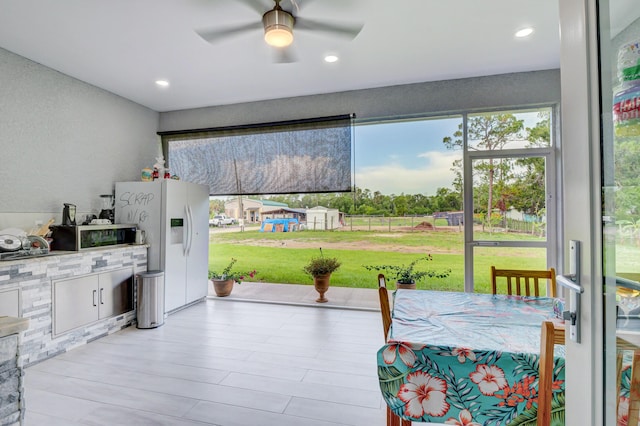 interior space featuring ceiling fan, white refrigerator with ice dispenser, stainless steel microwave, and recessed lighting