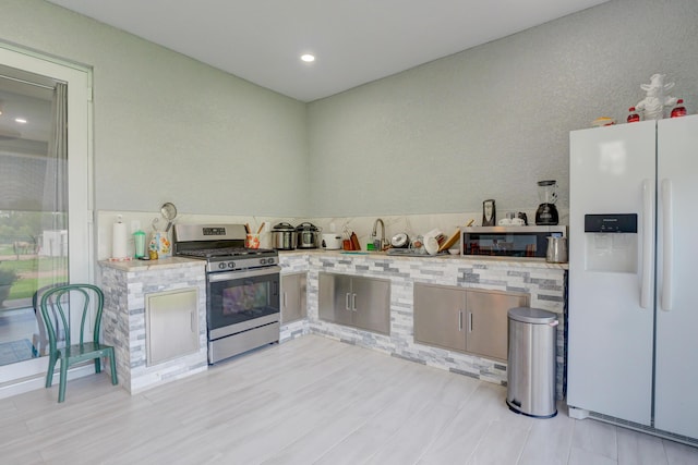 kitchen featuring light wood-type flooring, appliances with stainless steel finishes, and light stone counters