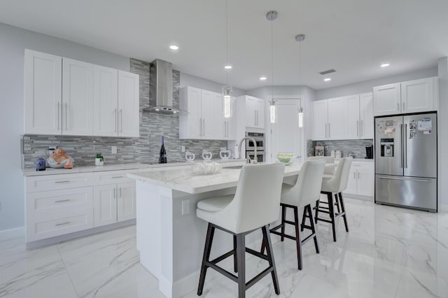 kitchen with stainless steel appliances, white cabinetry, and wall chimney range hood