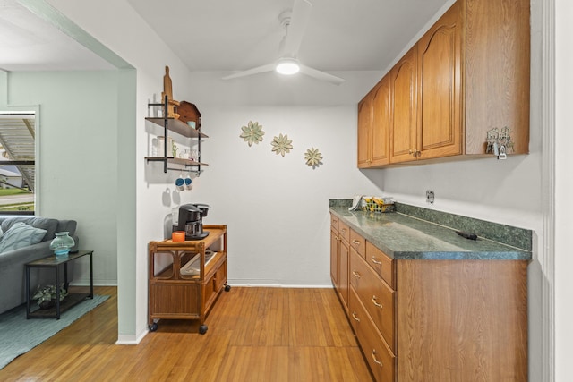 306 Fernandina St, Fort Pierce, FL 34949 - kitchen featuring dark countertops, light wood-style floors, brown cabinetry, a ceiling fan, and baseboards