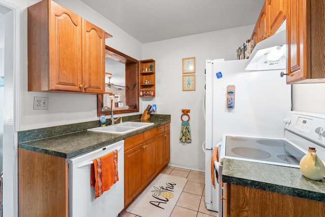 kitchen with dark countertops, white appliances, light tile patterned flooring, and a sink