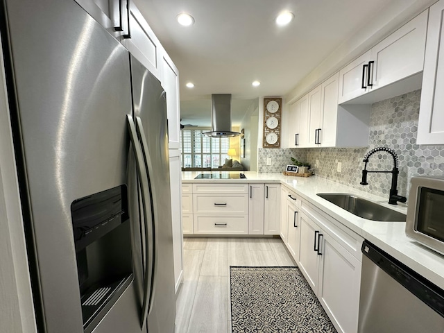 kitchen with sink, tasteful backsplash, appliances with stainless steel finishes, white cabinets, and island exhaust hood