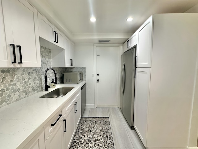 kitchen featuring appliances with stainless steel finishes, sink, light stone countertops, and white cabinets