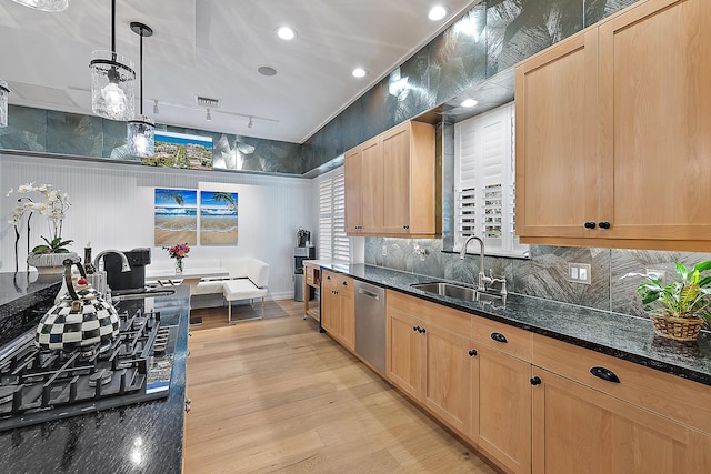 kitchen with light brown cabinetry, a sink, stainless steel dishwasher, dark stone counters, and light wood finished floors