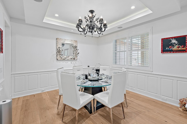 dining area featuring recessed lighting, an inviting chandelier, light wood-style flooring, and a tray ceiling