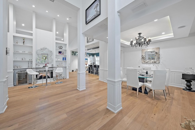 interior space featuring visible vents, built in features, decorative columns, light wood-style flooring, and a decorative wall