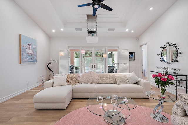 living area featuring a tray ceiling, light wood-style floors, and a ceiling fan