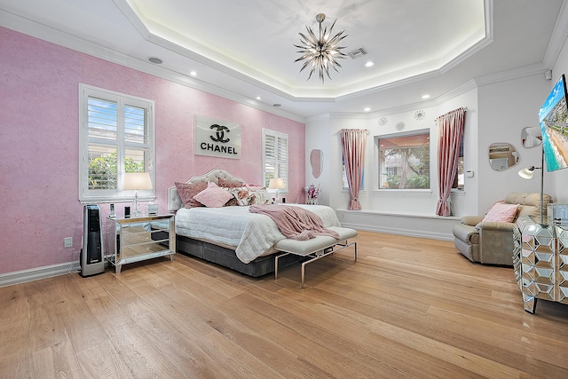 bedroom featuring visible vents, light wood-style flooring, a raised ceiling, and ornamental molding