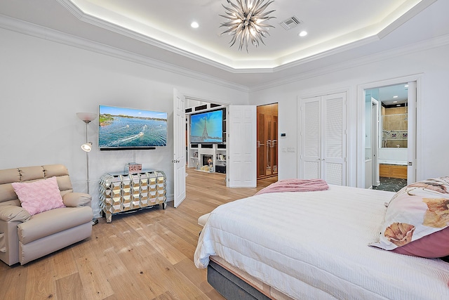 bedroom with visible vents, a raised ceiling, ornamental molding, and light wood finished floors