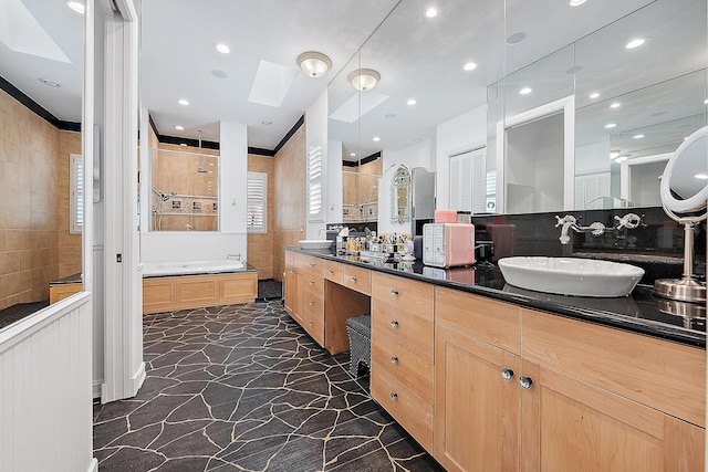 bathroom featuring tile walls, a tile shower, recessed lighting, a skylight, and vanity